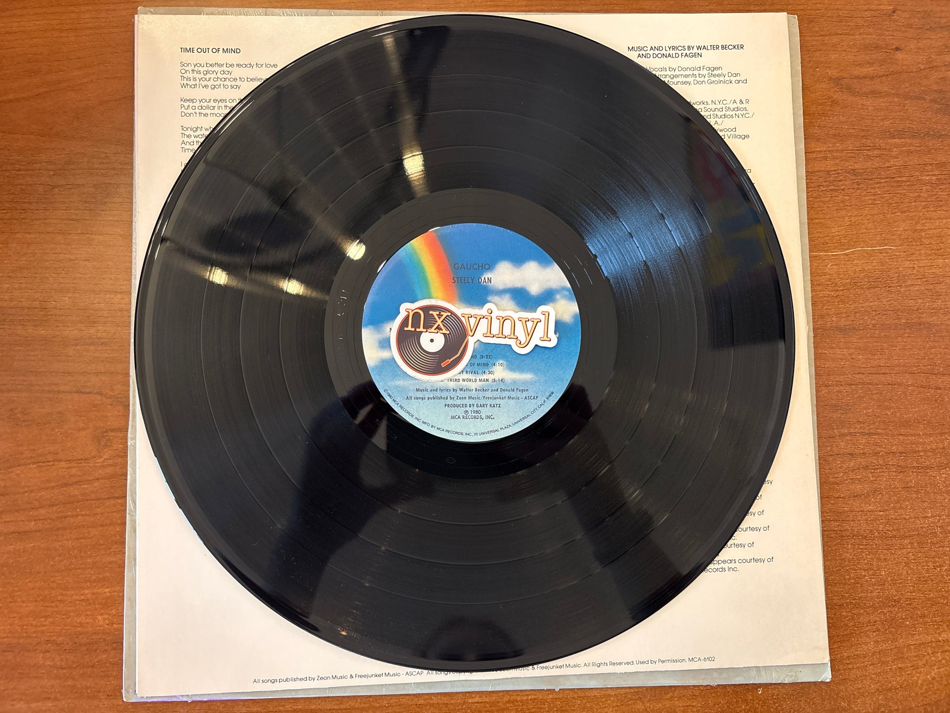 Vinyl record with a rainbow label on a wooden surface
