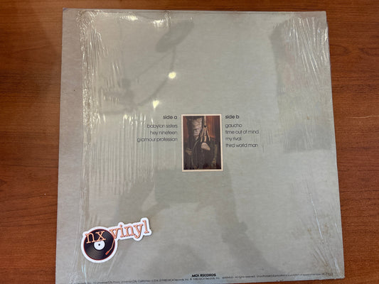 Vinyl record cover with text and a small photo on a wooden surface