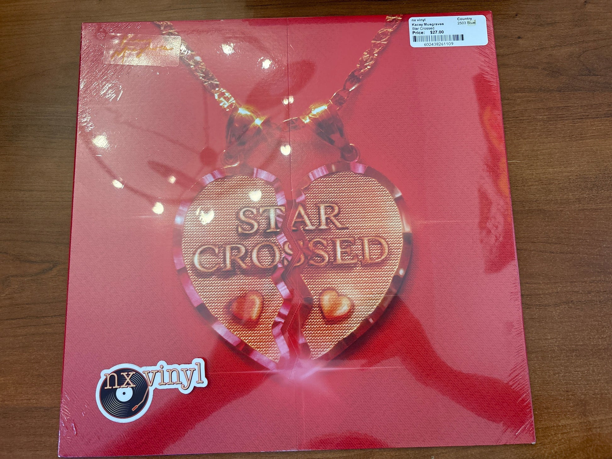 Vinyl record with 'Star Crossed' heart-shaped pendant on red cover