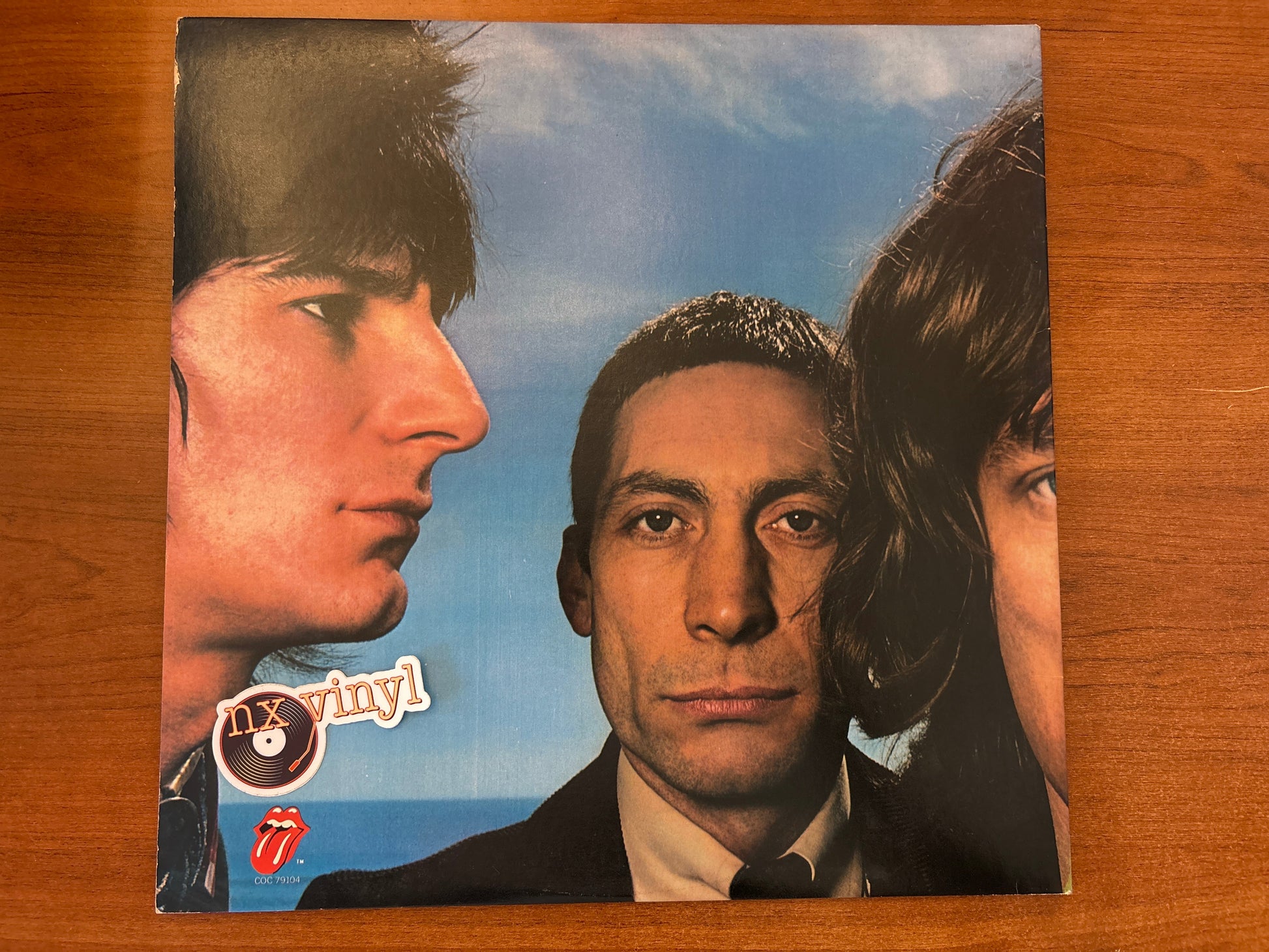 Album cover with three faces against a blue sky, featuring 'n' vinyl and The Rolling Stones logos.