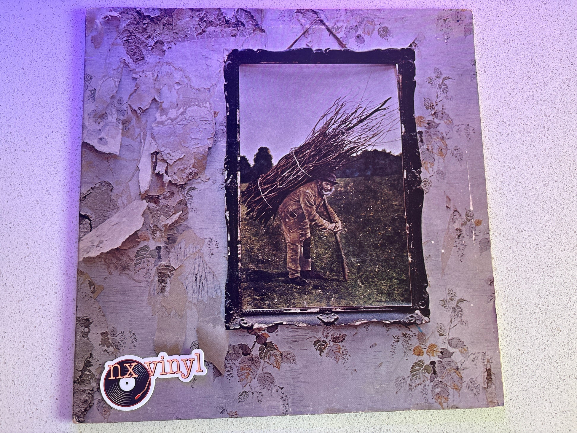 Vinyl record cover with distressed texture and central image of a person with a bundle of sticks.