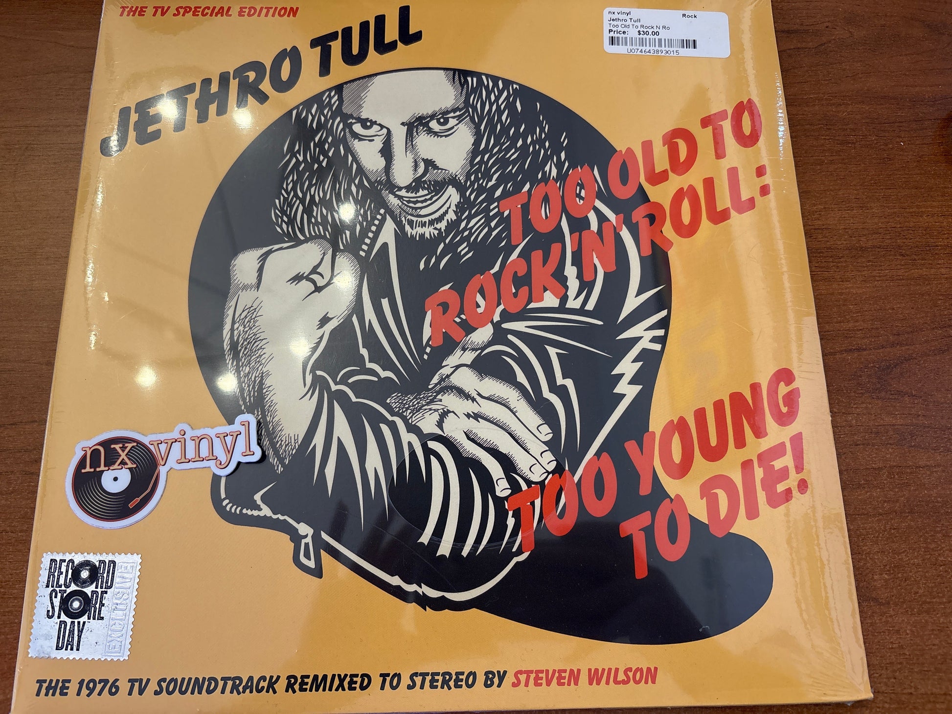 Vinyl record cover for Jethro Tull's 'Too Old to Rock 'n' Roll: Too Young to Die' on a wooden surface.