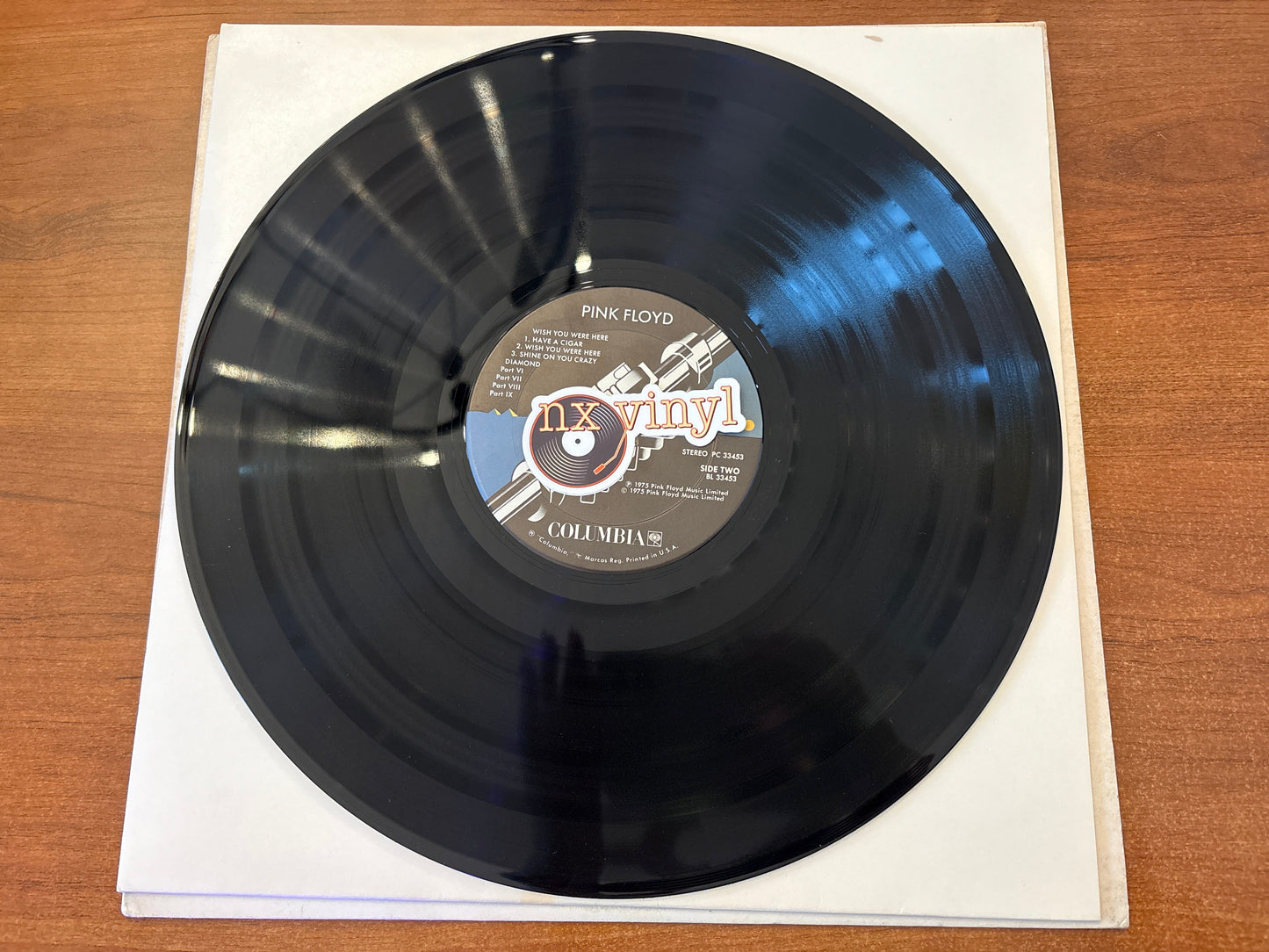 Vinyl record with a label on a white sleeve on a wooden surface
